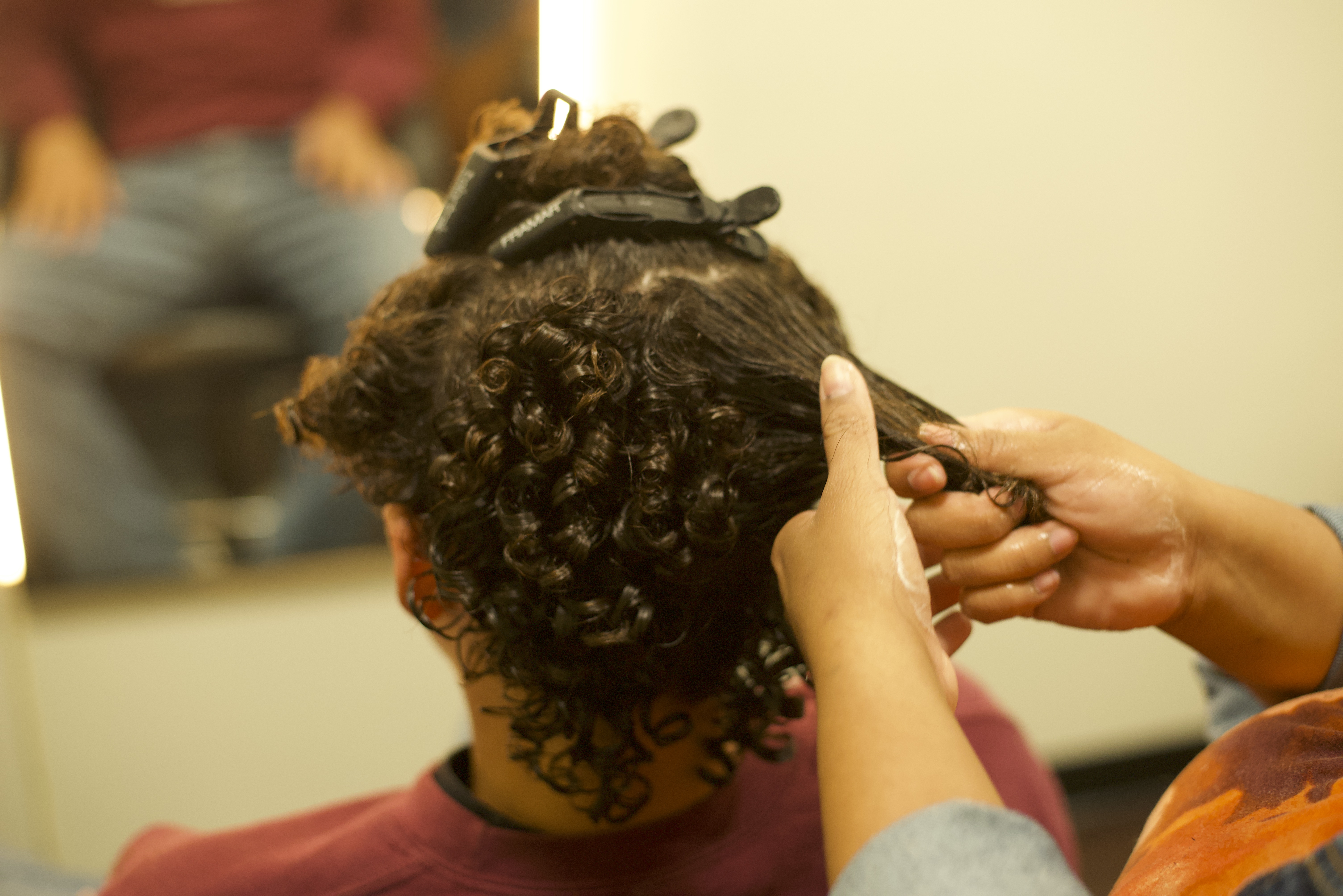 Stylist pulling clients hair to add curly texture